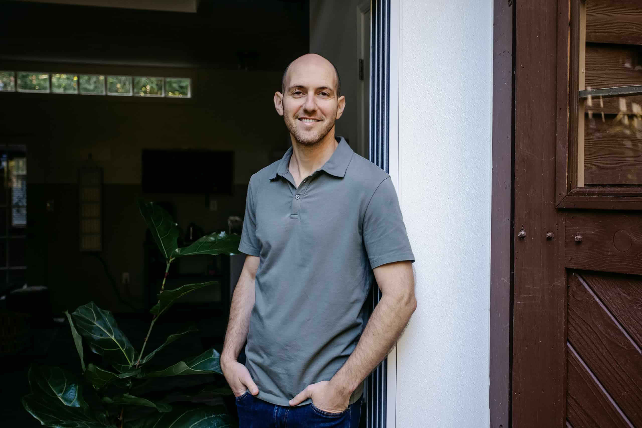 Yoni standing by the doorway of his studio, calm and grounded in natural light.